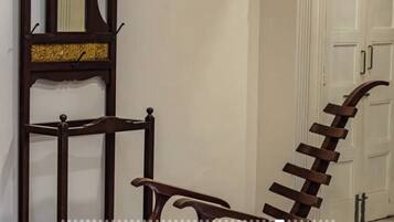 A hallway with a wooden chair and a metal ladder leaning against a wall.