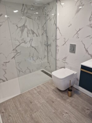 A modern bathroom with a glass shower enclosure, a white toilet, and a wooden floor. - Ocean Paradise Santa Luzia (Funchal)
