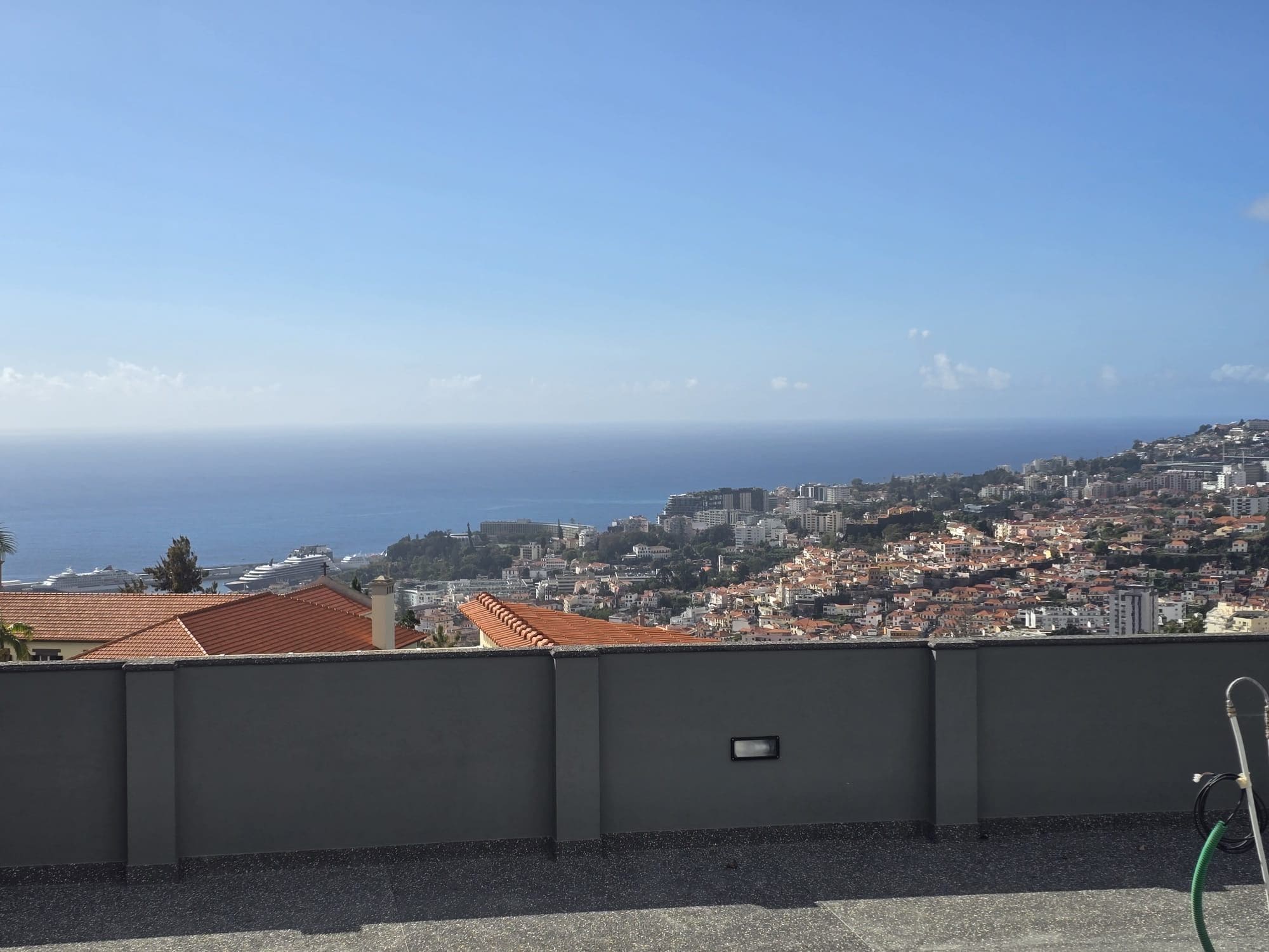 A rooftop view overlooking a coastal cityscape with buildings and the sea.