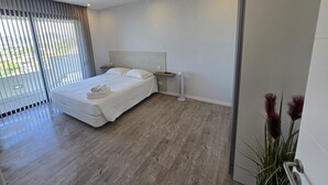 A modern bedroom with a bed, bedside table, and a view through the window. - Ocean Paradise Santa Luzia (Funchal)