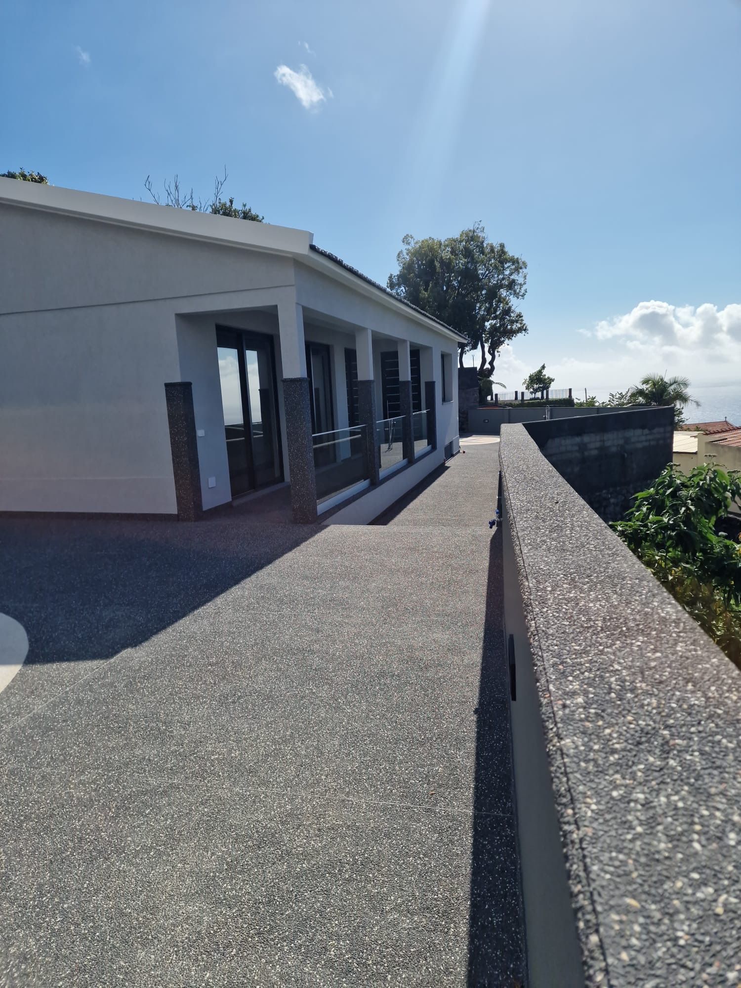 A modern building with a flat roof, large windows, and a paved walkway.