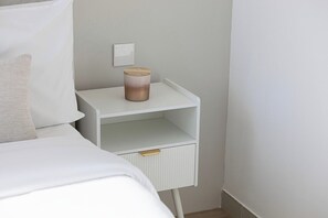 A white bedside table with a candle, a power outlet, and a drawer. - Ocean & Palm Views / Infinity pool / High floor (Dubai)