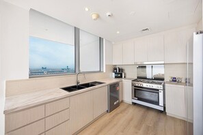 A modern kitchen with a large window, stainless steel appliances, and light wood cabinetry. - Ocean & Palm Views / Infinity pool / High floor (Dubai)
