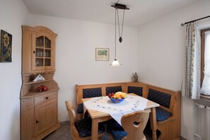 A dining area with a wooden table, chairs, a cabinet, and a hanging light fixture. - Vacation rental with a rooftop terrace and mountain views. Perfect for the Zugspitze and Eibsee. (Grainau)