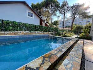 A swimming pool with stone edging, surrounded by a hedge and a building with a window. - Room-sea Pearl Studios Golem - First-flo (Golem)
