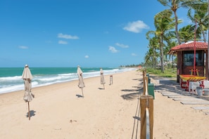 Una playa con sombrillas, una estructura de madera y palmeras.