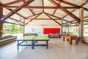 Un espace de loisirs intérieur comprenant une table de billard, un baby-foot et un meuble rouge.