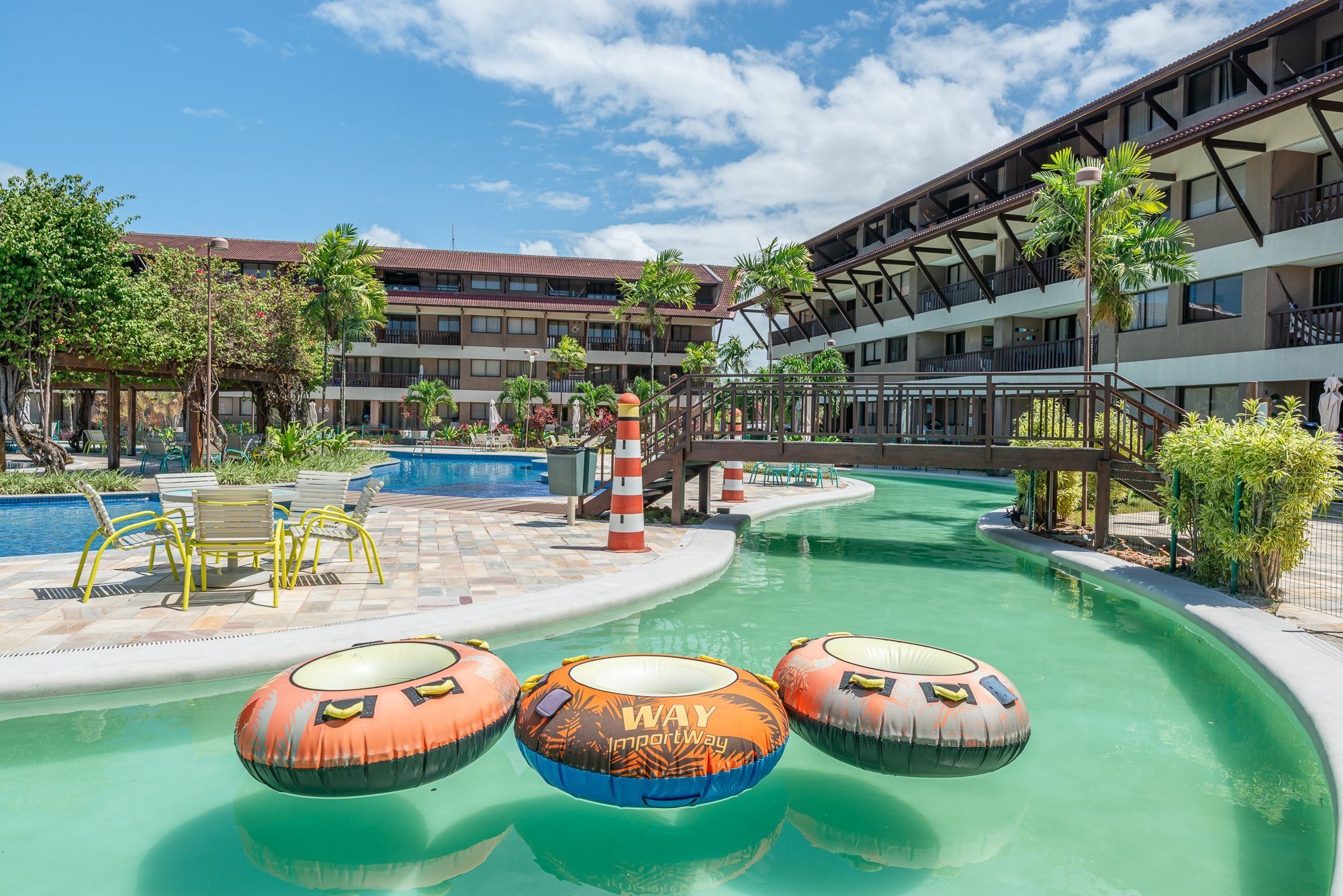 Zona de piscina de hotel con tobogán de agua, sillas de descanso y balsas inflables.