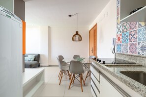 A modern kitchen with a dining area, a built-in oven, and a patterned backsplash.