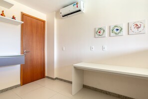 Une pièce avec une porte en bois, un banc blanc et des œuvres d’art accrochées au mur.