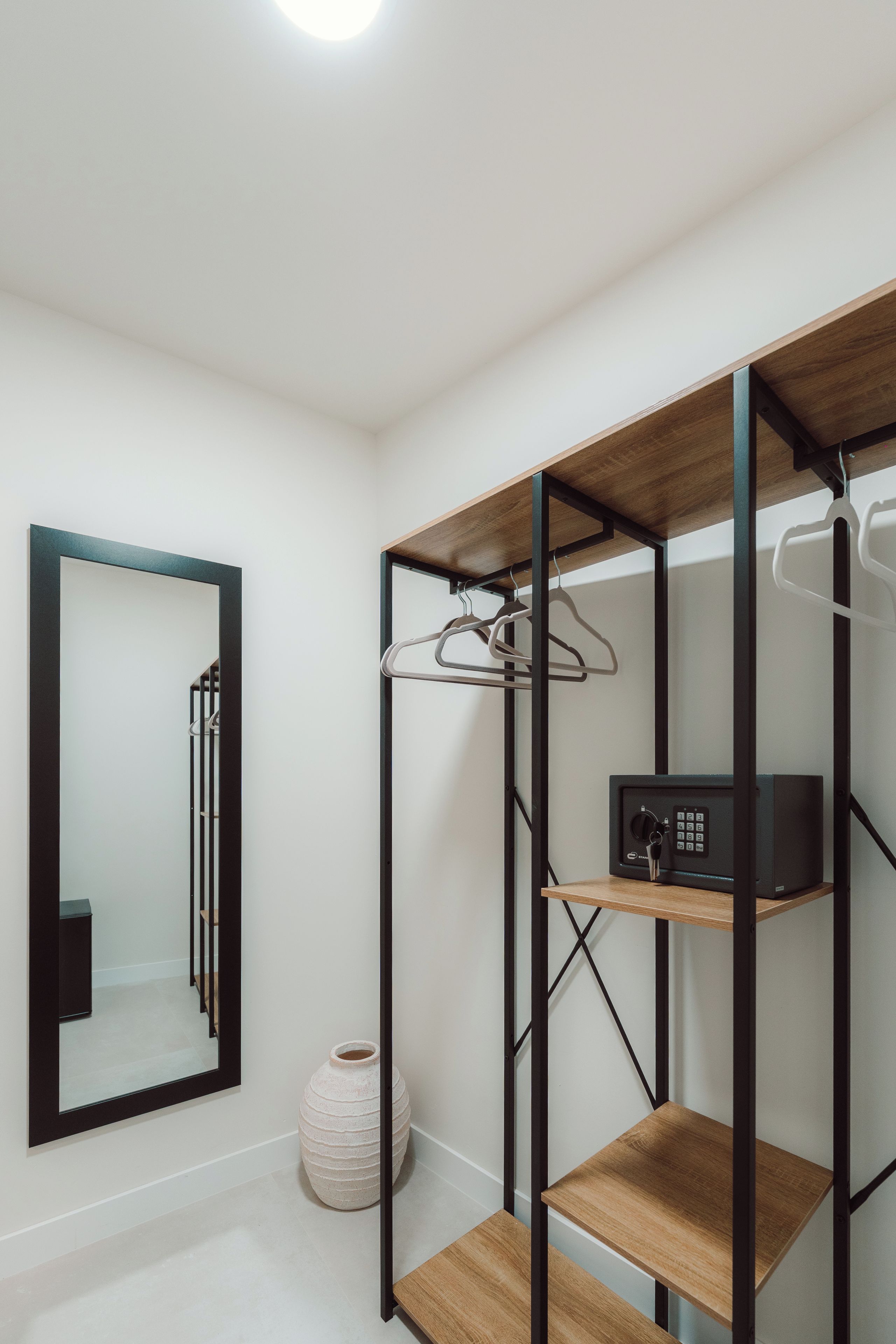 A modern room with a wooden shelving unit, a mirror, and a small white vase.