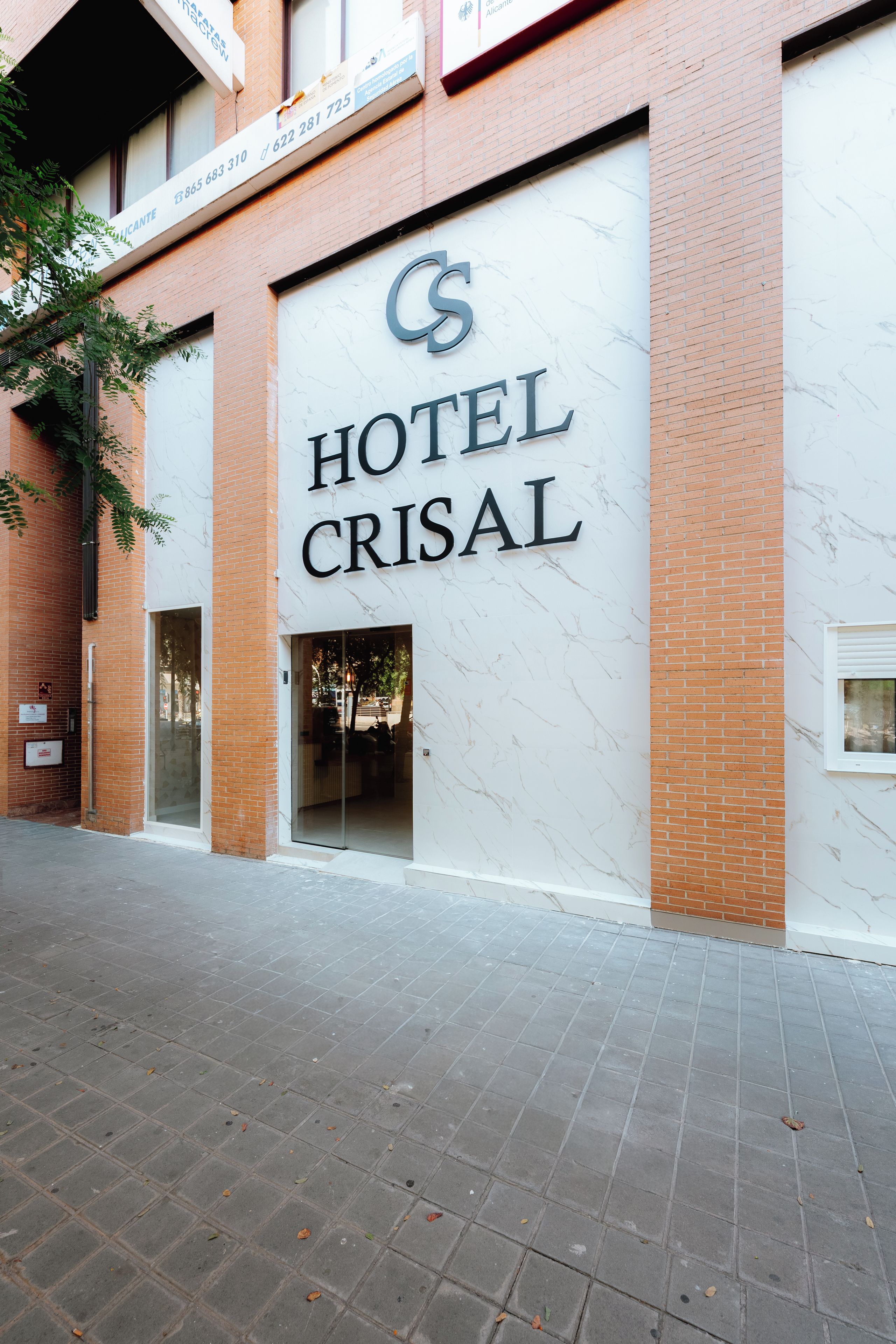 A hotel entrance with a marble facade and a glass door.