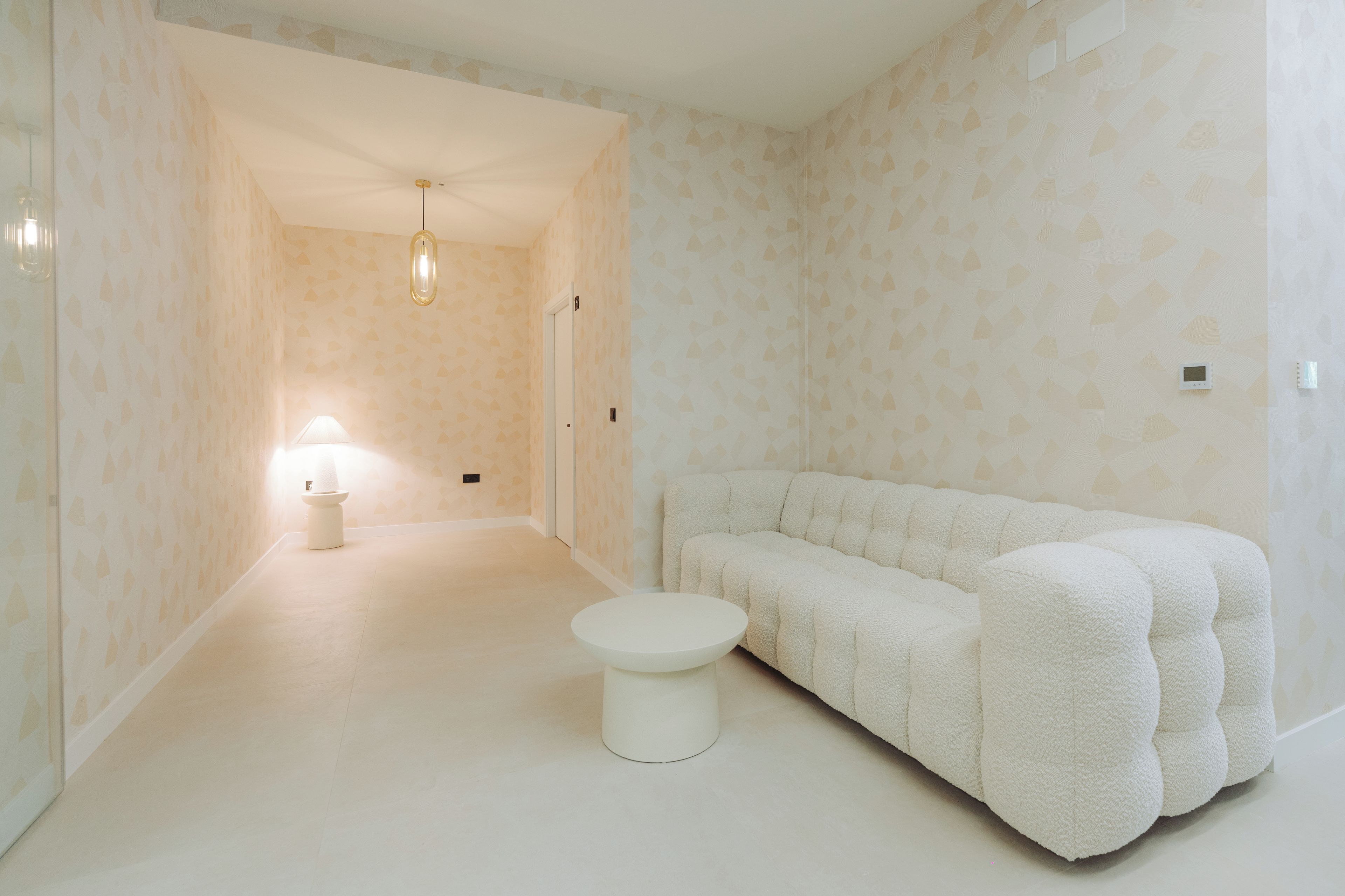 A minimalist room with a white sofa, a round table, and a lamp.