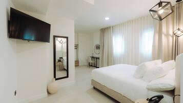 Habitación de hotel moderna con una cama grande, un televisor de pantalla plana, un espejo y un escritorio con silla.