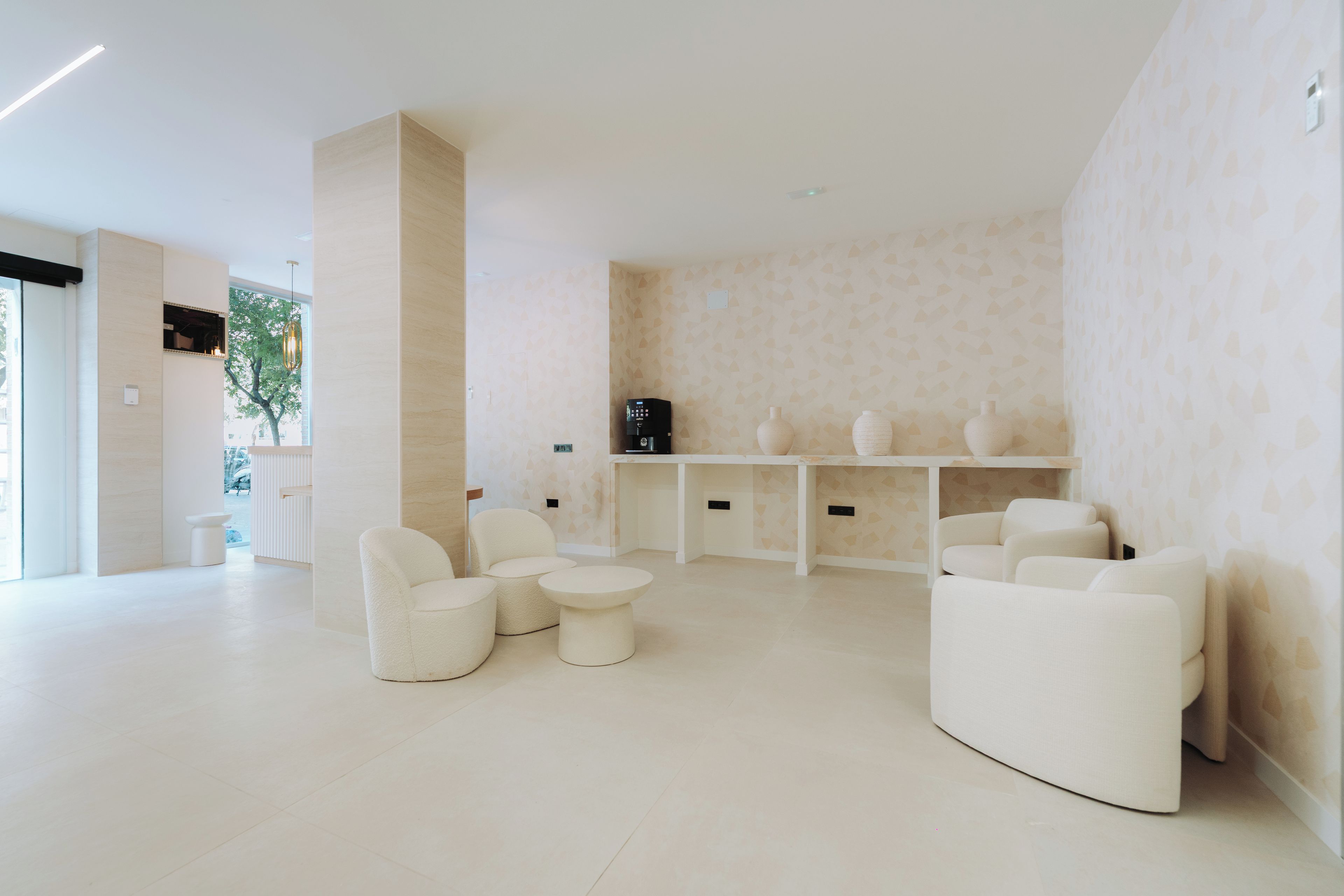 A modern, minimalist lounge area with seating arrangements and a coffee machine.