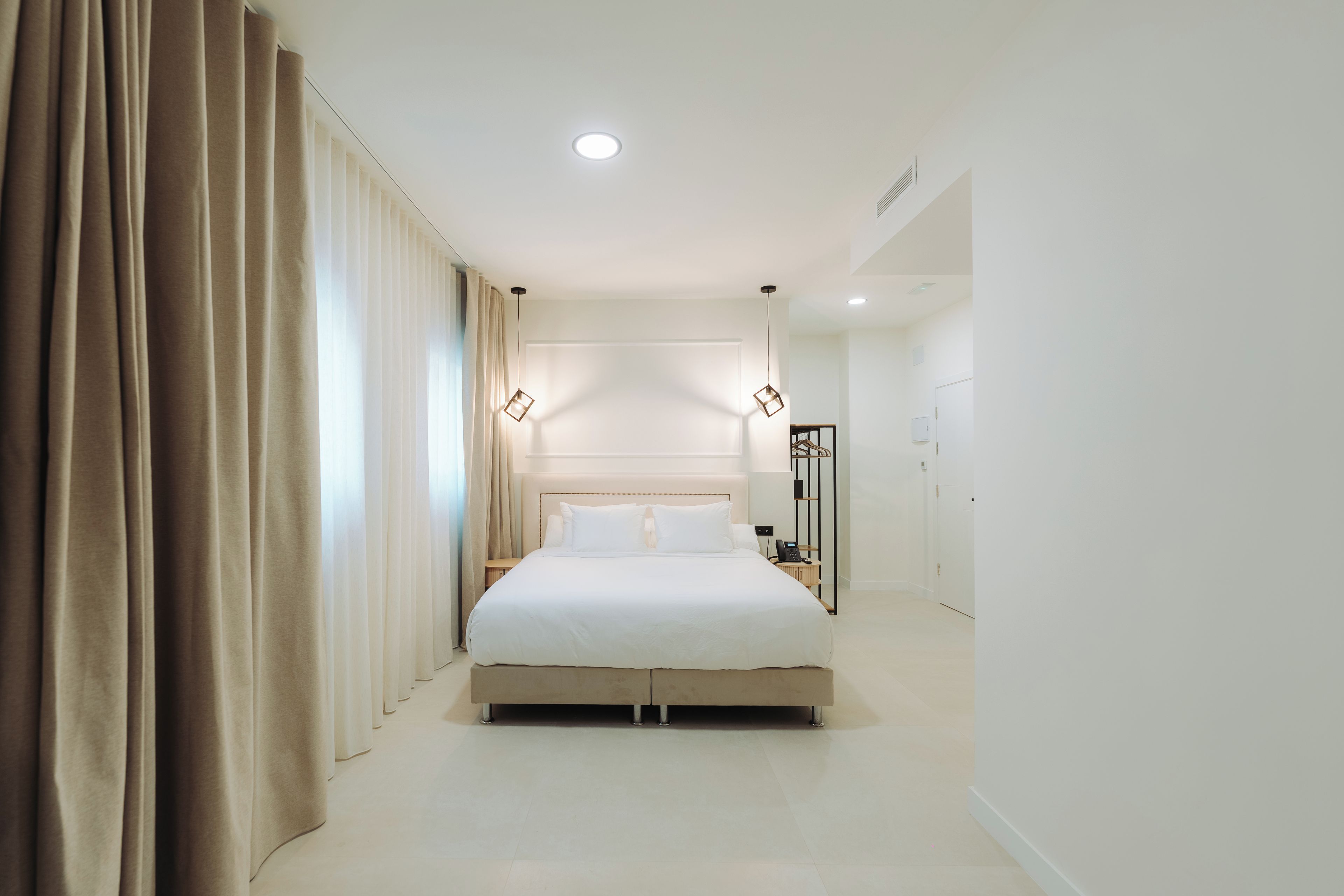 Una habitación de hotel moderna con una cama grande, una mesita de noche, un armario y un baño a la vista.