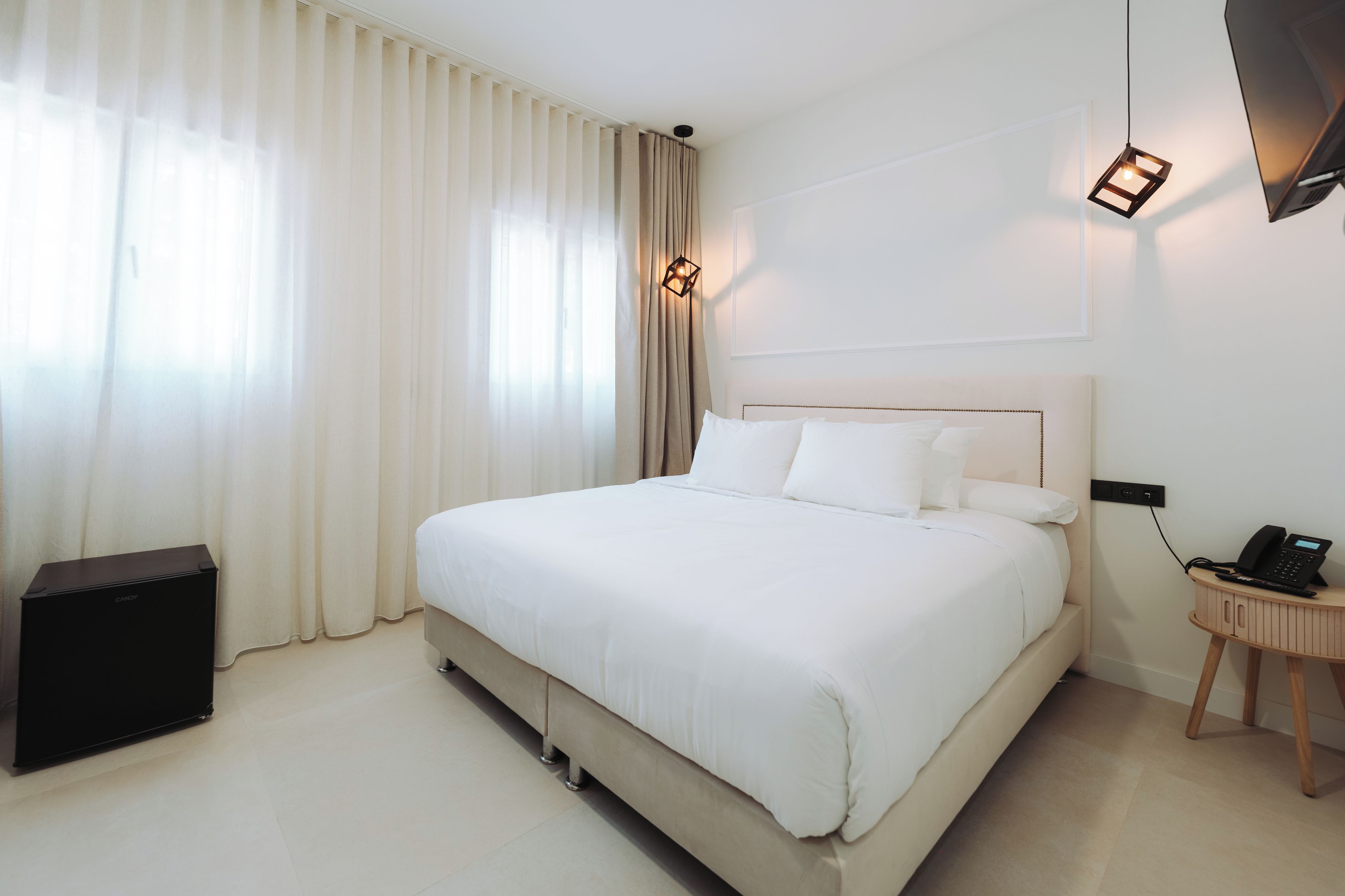 Een hotelkamer met een groot bed, een nachtkastje met een telefoon en een lamp.