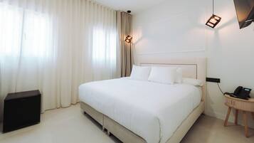 Een hotelkamer met een groot bed, een nachtkastje met een telefoon en een lamp.