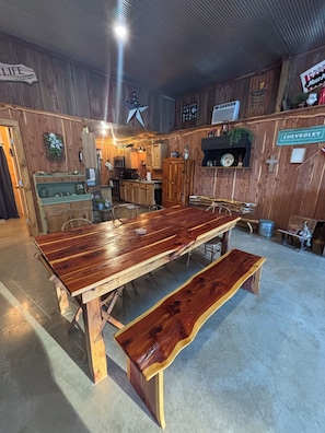 A rustic wooden interior with a large dining table and benches, wooden walls, and a Chevrolet sign. - Coyote's Den Camp House at Mark Twain Lake (Center)