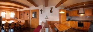 Ein Holzinnenraum mit Essbereich, Küche und einem Kruzifix an der Wand.