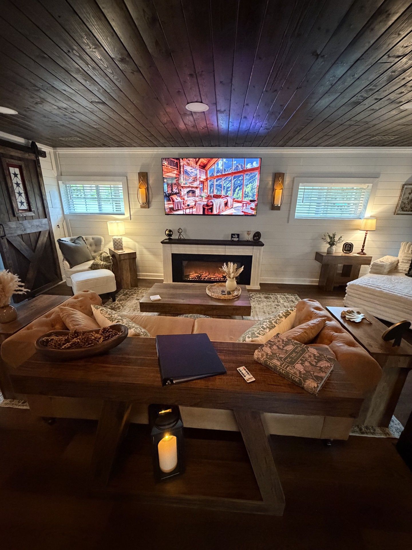 A cozy living room with a fireplace, comfortable seating, and a television mounted on the wall.