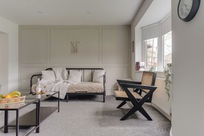 A bedroom with a bed, a side table with a bottle and fruit, a chair, and a window with a view of houses. - Contractors | 3BDR | Parking | Near Universal (Brogborough)
