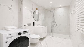 Ein modernes Badezimmer mit Waschmaschine, Toilette und Duschkabine.