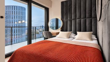 Ein modernes Hotelzimmer mit einem großen Bett, einem runden Spiegel und Blick auf die Stadt.