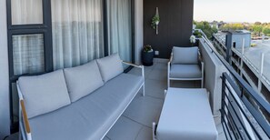 Ein Balkon mit einer Couch, Stühlen und einem kleinen Tisch.
