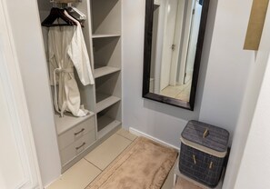 Ein begehbarer Kleiderschrank mit offenen Regalen, einer Kleiderstange und einem Spiegel.