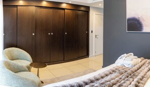 Ein modernes Schlafzimmer mit großem Kleiderschrank, einer Couch, einem kleinen Tisch und einem Bett mit flauschiger Decke.