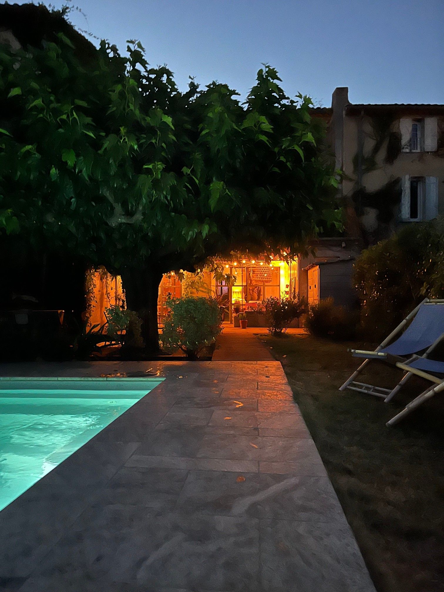 A pool area with a pathway leading to a building with warm lighting.