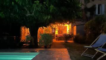 A pool area with a pathway leading to a building with warm lighting.