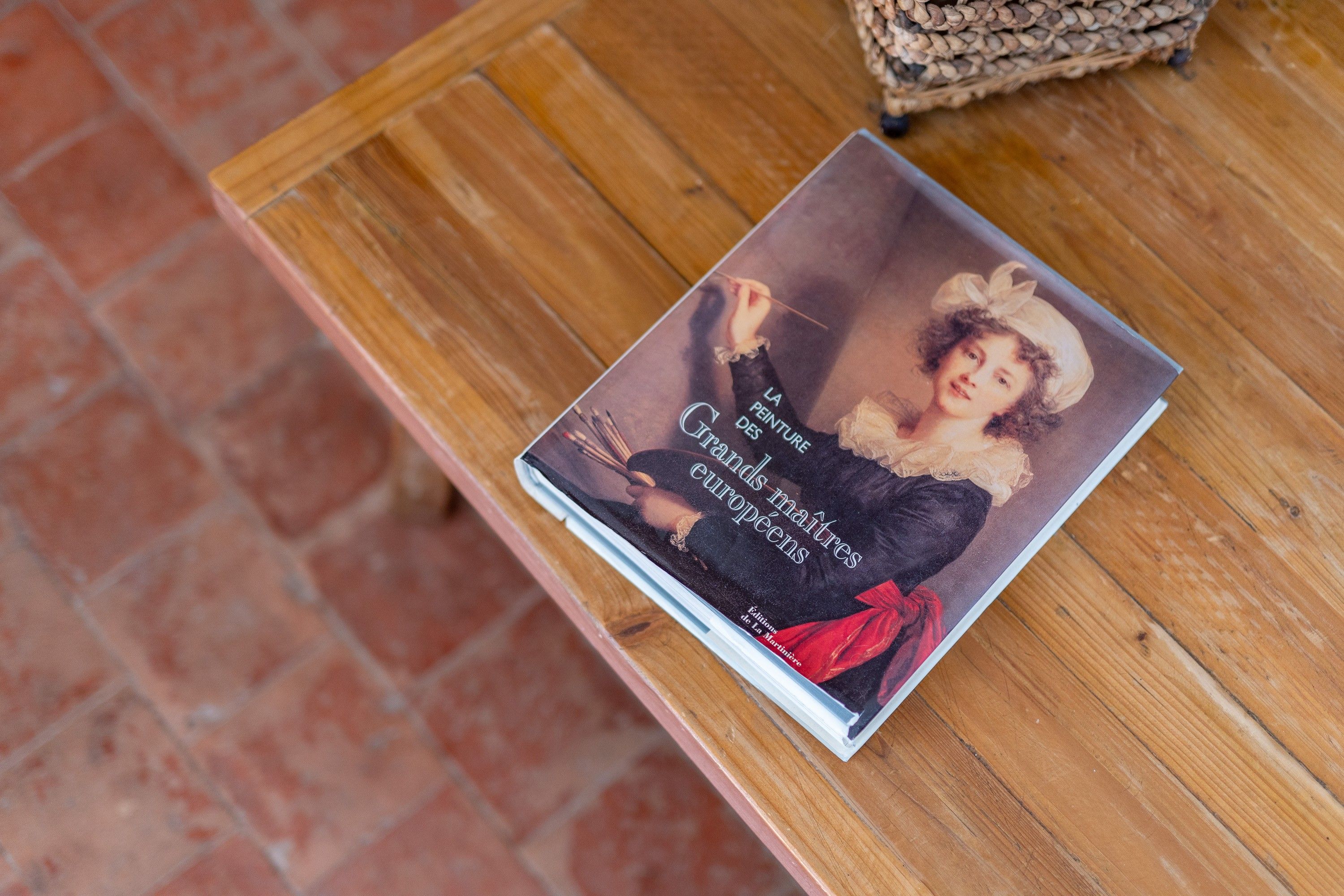 A book titled 'La Peinture des grands maîtres europeens' on a wooden table.