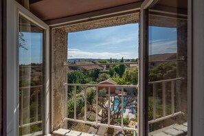 A balcony with a view of a swimming pool, greenery, and distant buildings.