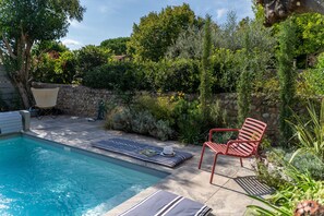 A swimming pool with lounge chairs and a stone wall.
