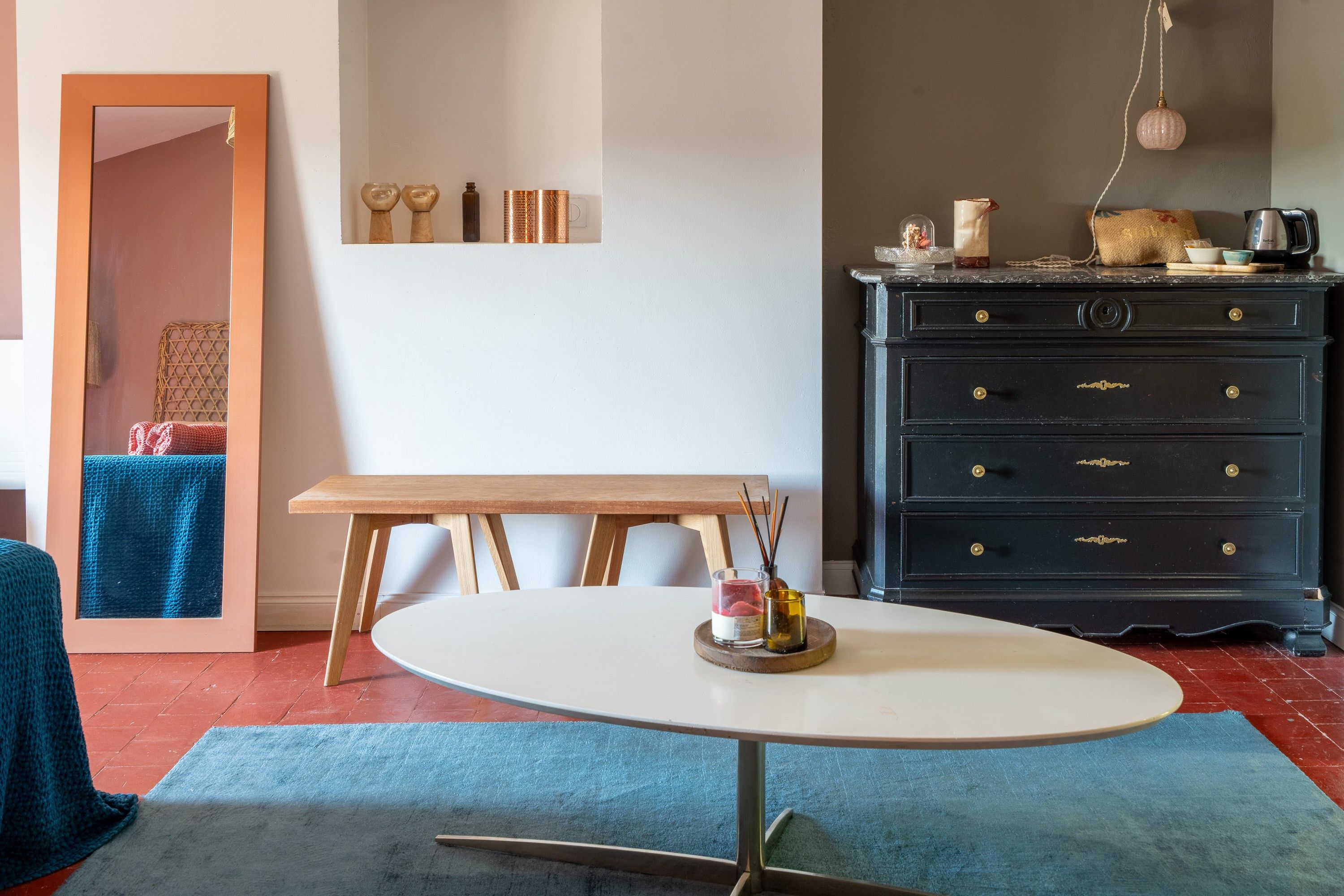 A room with a round table, a dresser, and a mirror.