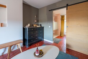 A room with a black dresser, a bench, a small table with a candle, and a sliding door leading to another room. - Guest Room 'Suite 55' with Wi-Fi (Tulette)