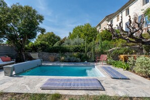 A swimming pool with lounge chairs and a stone wall. - Guest Room 'Suite 55' with Wi-Fi (Tulette)