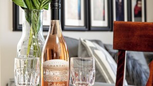 Ein Tisch mit einer Flasche Chateau Chantal, zwei Gläsern und einer Blumenvase.