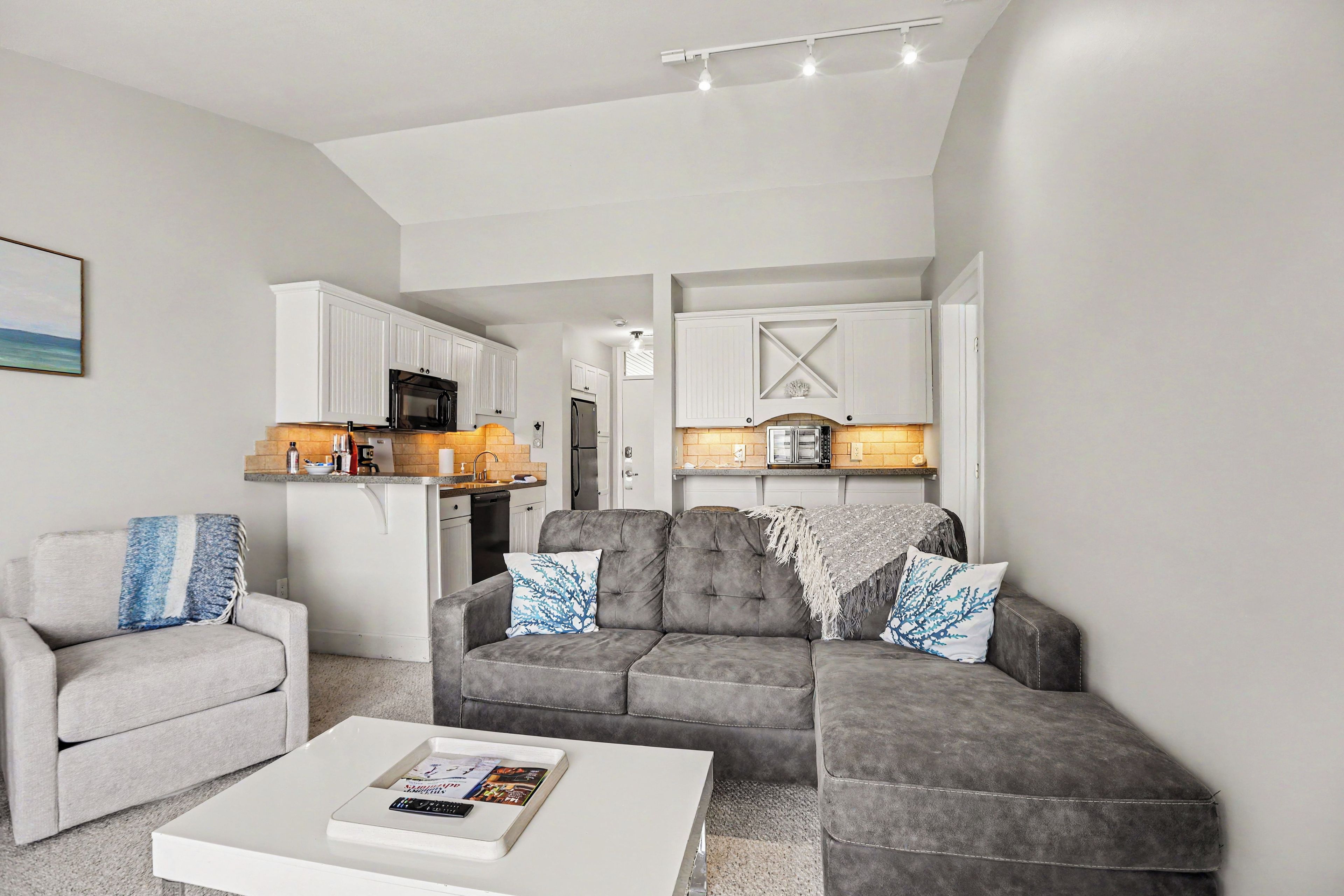 Een moderne woonkamer met een grijze bank, een witte salontafel en een grijze fauteuil.