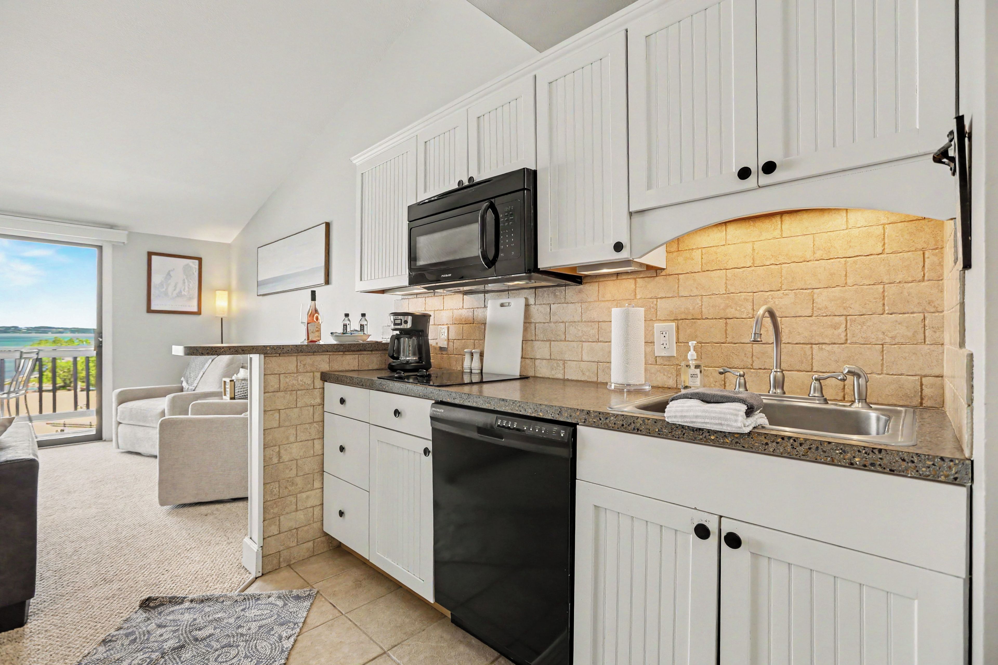 A modern kitchen with white cabinetry, a black dishwasher, a microwave, and a sink.