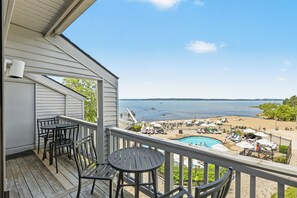 A balcony with a view of a swimming pool and beach.