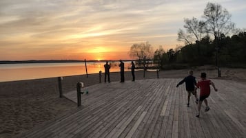 Una passerella in legno che conduce a una spiaggia, con un tramonto sullo sfondo.