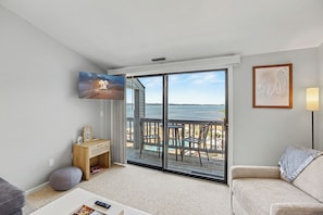 A living room with a large sliding glass door leading to a balcony with a view of the ocean. - 🏖 Top-floor Bay-view 1BR @ The Shores Grand Traverse Resort Sleeps 6 (Williamsburg)
