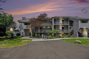 A multi-story building with a central courtyard, balconies, and a driveway leading to the entrance.