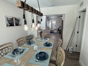 A dining area with a wooden table set for four, surrounded by chairs. - New Construction.  Sunny Escape Near Anna Maria : 3BR/2BA Home with Resort Pool! (Bradenton)