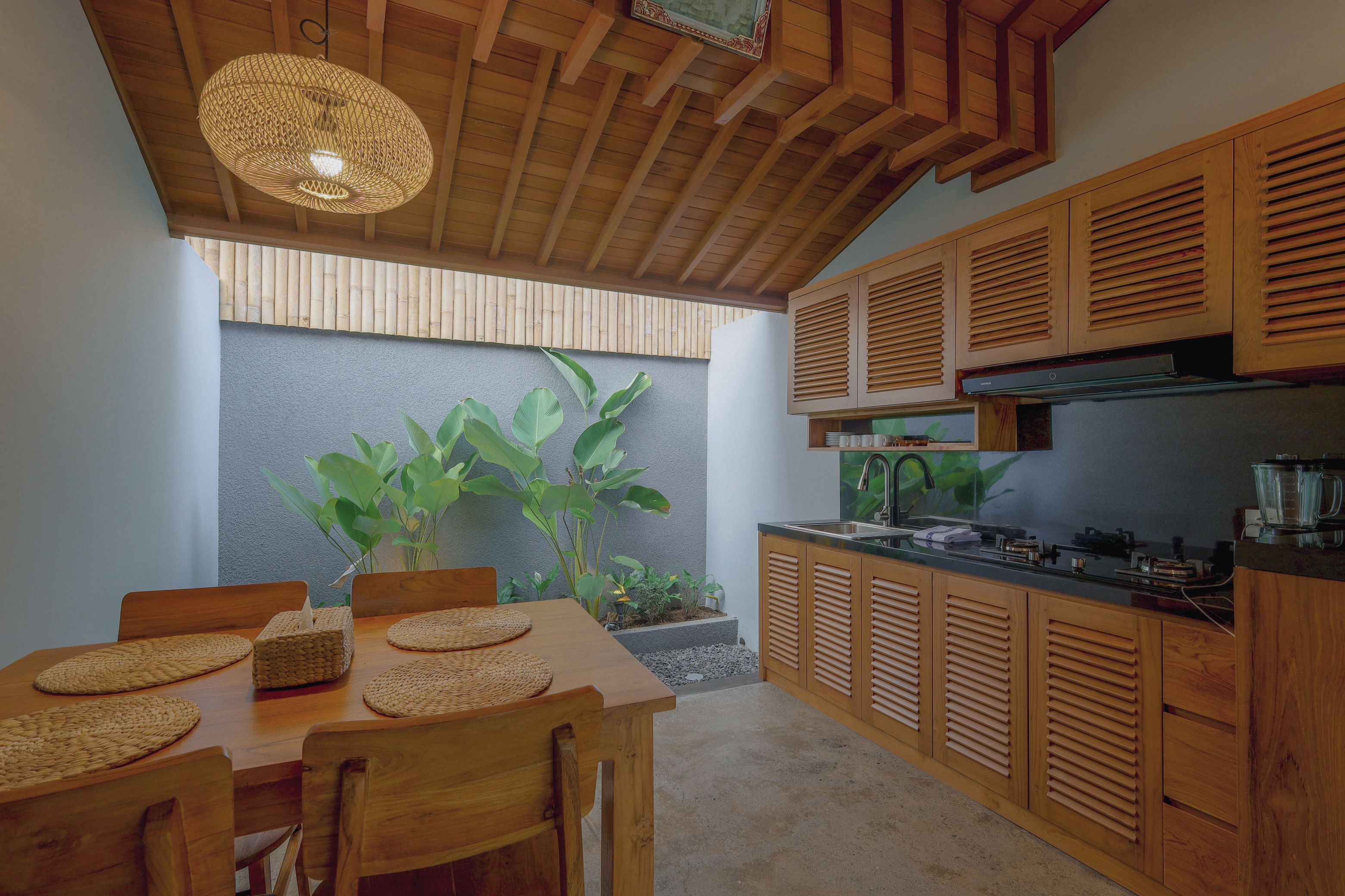 Una cocina moderna con armarios de madera, estufa integrada y comedor con mesa y sillas.