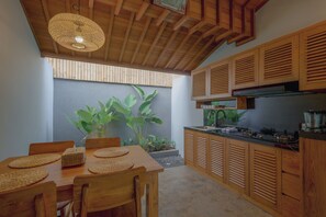 Une cuisine moderne avec des meubles en bois, une cuisinière encastrée et un coin repas comprenant une table et des chaises.