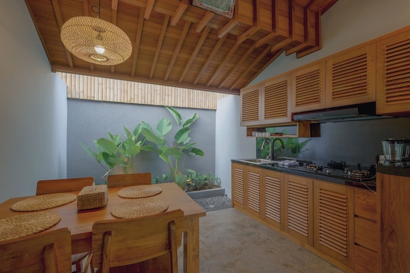 A modern kitchen with wooden cabinets, a built-in stove, and a dining area with a table and chairs.